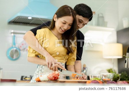 Portrait young couple in love helping to cook In a romantic atmosphere at home with smile face. Portrait young couple in love helping to cook In a romantic atmosphere at home with smile face. 76117686