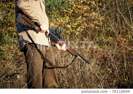 Hunter hunting in the forest with a hunting rifle. A man with a gun. Hunter hunting in the forest with a hunting rifle. A man with a gun. 76118694