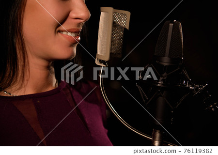 Young woman singer in front of microphone. 76119382