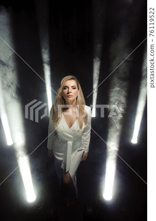 Beautiful female model posing at studio in the lights. 76119522