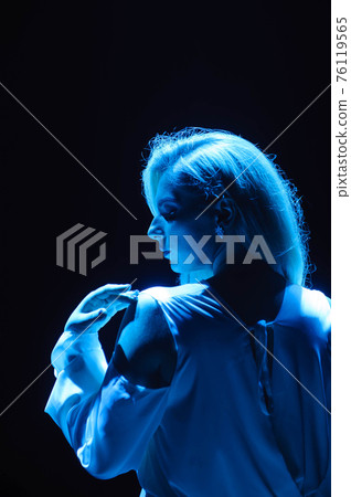 Beautiful moman in flying white dress in the light of blue light. Flowing fabric. Light white cloth 76119565