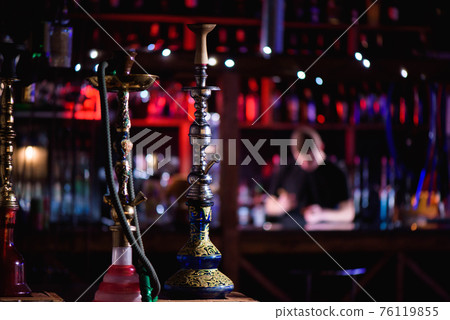 Barman fills black burnt ceramic bowl for hookah smoking different types of tobacco. Barman fills black burnt ceramic bowl for hookah smoking different types of tobacco. 76119855
