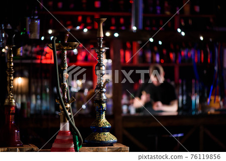 Barman fills black burnt ceramic bowl for hookah smoking different types of tobacco. 76119856