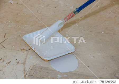 Roller is wetted in a liquid primer in a plastic container before painting the walls with paint 76120598