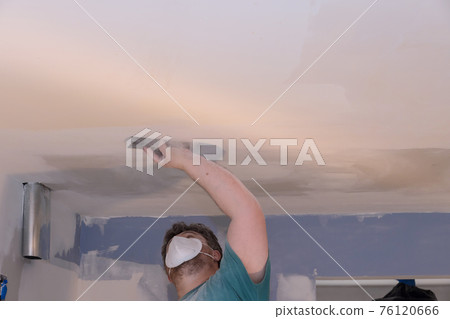 Contractor using sand trowel sanding the ceiling drywall Contractor using sand trowel sanding the ceiling drywall 76120666