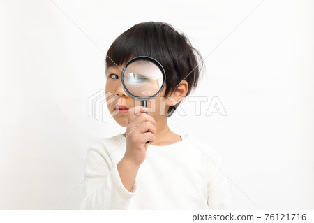 A boy with a magnifying glass 76121716