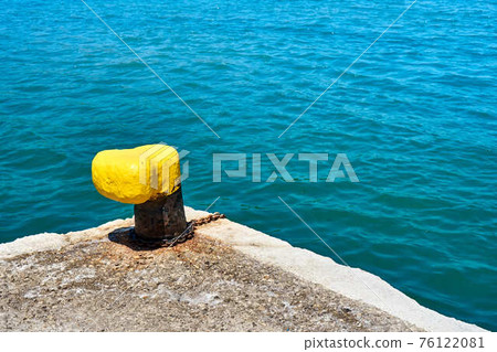 Yellow mooring bollard on grey concrete pier 76122081