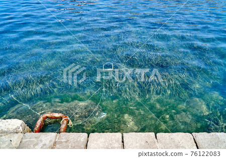 Rusty mooring bracket on grey concrete pier edge 76122083