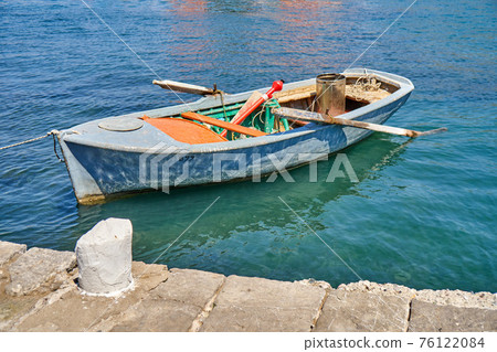 Boat with oars moored to pier on sea Boat with oars moored to pier on sea 76122084