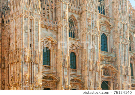 Famous church Milan Cathedral Duomo di Milano with Gothic spires and white marble statues. Top tourist attraction on piazza in Milan Lombardia Italy. Wide angle view of old Gothic architecture and art 76124140