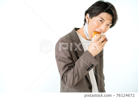 A casual businessman eating a hamburger with a urethane mask on his chin A casual businessman eating a hamburger with a urethane mask on his chin 76124672