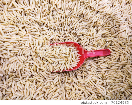 Dry raw italian penne pasta with scoop, whole wheat ingredient Dry raw italian penne pasta with scoop, whole wheat ingredient 76124985