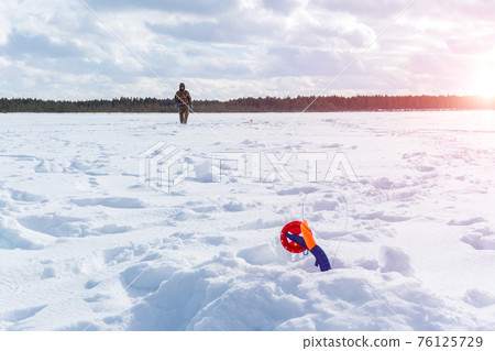 winter landscape of fishermen on the ice of the river on a sunny day. winter sports winter landscape of fishermen on the ice of the river on a sunny day. winter sports 76125729