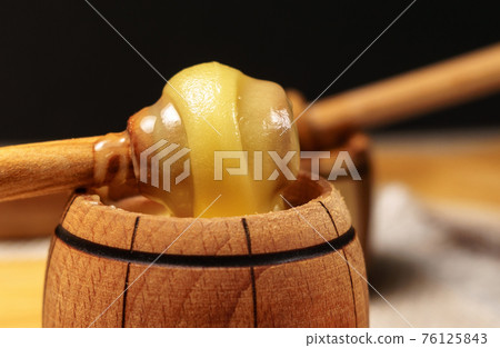 wooden stick to bowl with liquid floral fresh honey. Healthy organic honey dripping, pouring from honey wooden spoon. wooden stick to bowl with liquid floral fresh honey. Healthy organic honey dripping, pouring from honey wooden spoon. 76125843