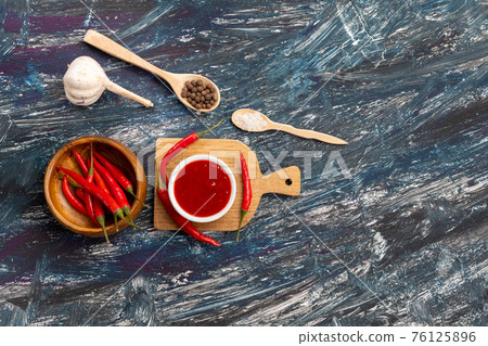 Composition with chilli pepper sauce, garlic and sauce on black background. top view copy space Composition with chilli pepper sauce, garlic and sauce on black background. top view copy space 76125896