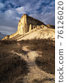 Beautiful white mountain peak lit by sun. White clouds and blue sky on background. Epic rock formation 76126020