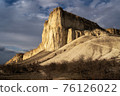Beautiful white mountain peak lit by sun. White clouds and blue sky on background. Epic rock formation 76126022