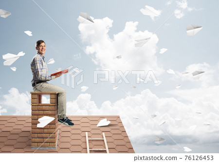 Handsome student guy reading book and paper planes flying in air 76126453