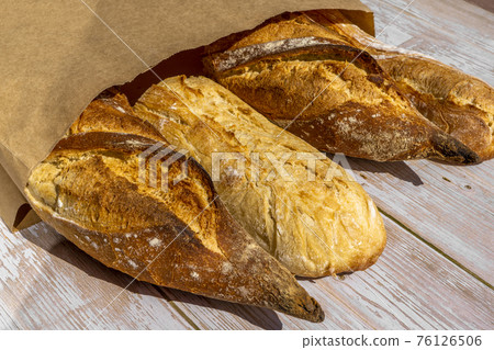 French traditional baguettes in paper bags on wooden table background. French traditional baguettes in paper bags on wooden table background. 76126506