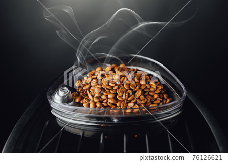 fresh roasted coffee beans with smoke in coffeemaker bean container, close-up view fresh roasted coffee beans with smoke in coffeemaker bean container, close-up view 76126621
