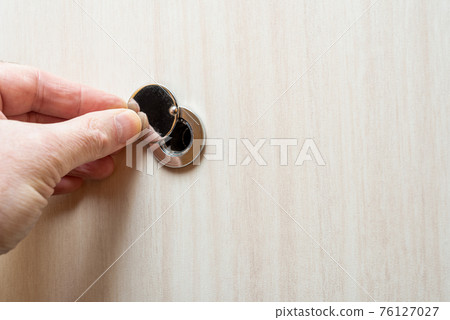 Close up - a human hand opens the peephole cover. 76127027