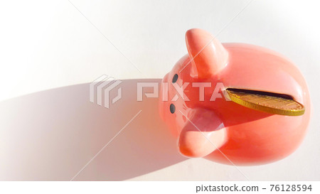 Top view over pink piggy bank with slot and inserted coin, on white background, savings and investment concept, copy space, space for text Top view over pink piggy bank with slot and inserted coin, on white background, savings and investment concept, copy space, space for text 76128594