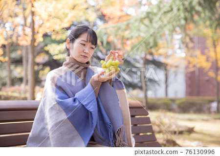 Woman with grapes in autumn park (problem) Woman with grapes in autumn park (problem) 76130996