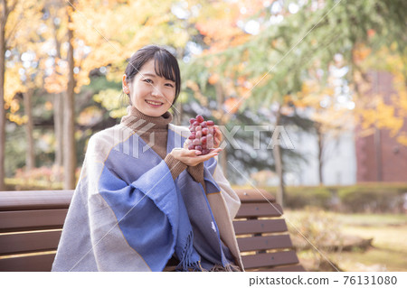Woman with grapes in autumn park Woman with grapes in autumn park 76131080