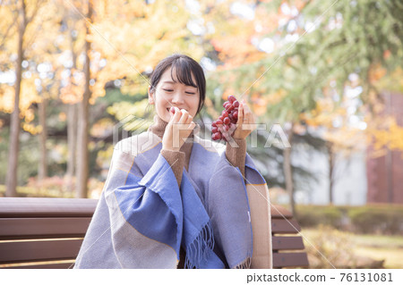 Woman with grapes in autumn park Woman with grapes in autumn park 76131081