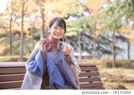 秋天公園裡帶葡萄的女人 76131084