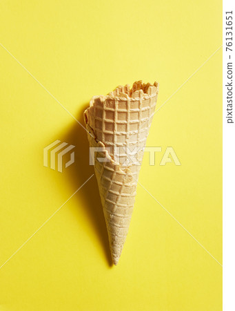 Sweet wafer cone on yellow background Sweet wafer cone on yellow background 76131651