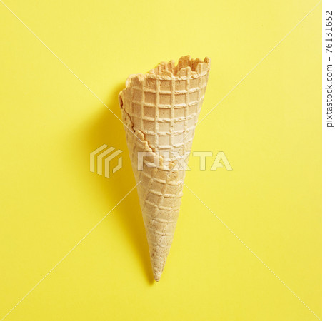 Sweet wafer cone on yellow background Sweet wafer cone on yellow background 76131652