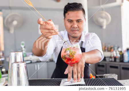 Bartender is making cocktail at counter bar. 76131995