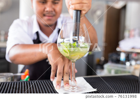 Bartender is making cocktail at counter bar. 76131998