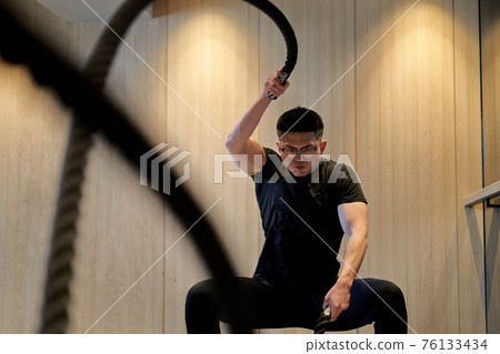 Asian man training on a battle rope Asian man training on a battle rope 76133434