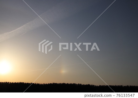 Contrails and halos in the setting sun 76133547