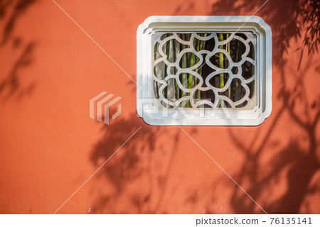 Chinese traditional window on a red wall in a park 76135141