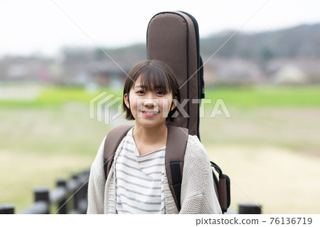Musician carrying a guitar 76136719