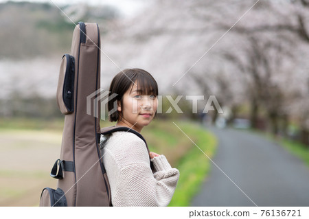 Musician carrying a guitar 76136721
