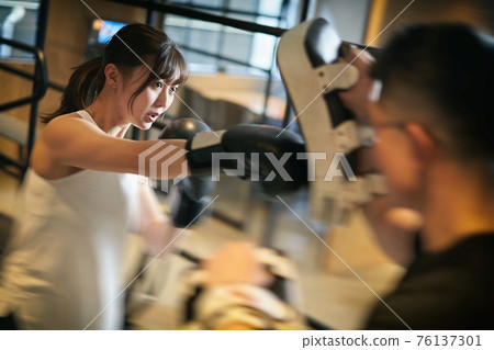 Asian woman learning kickboxing from a personal trainer 76137301