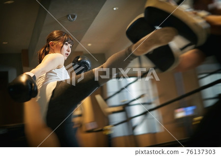 Asian woman learning kickboxing from a personal trainer 76137303
