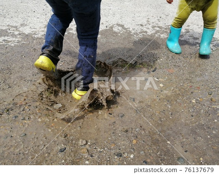 Child playing in a puddle Child playing in a puddle 76137679