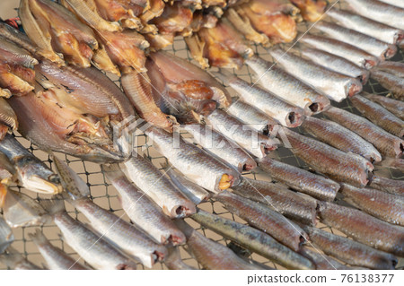 Row of traditional salted fresh fish drying in local market. Fresh food for cooking or sale. Fishery industry. Dead animal. Row of traditional salted fresh fish drying in local market. Fresh food for cooking or sale. Fishery industry. Dead animal. 76138377
