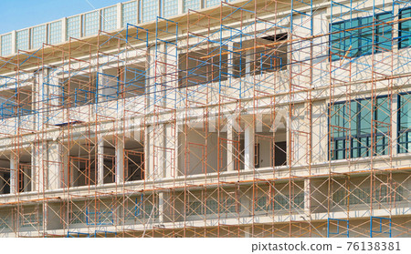 Scaffolding of house building. Lattice mast, cables or poles in busy industrial under construction site with cranes. Steel or metal structure. Development stucture architecture. Real estate. 76138381