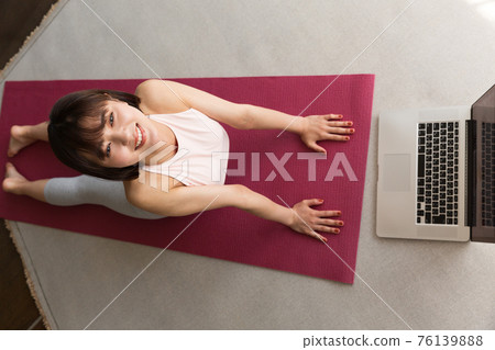 Woman stretching in front of a laptop 76139888