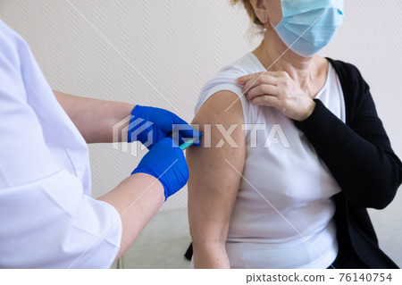 Woman being vaccinated in her hands on a white background in a hospital. Routine vaccination against 76140754