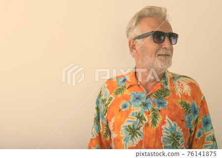 Studio shot of happy senior bearded tourist man smiling while thinking and wearing sunglasses 76141875