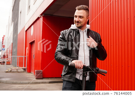 Young attractive man on electric scooter over red background 76144005