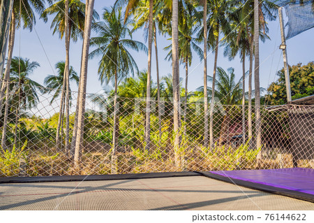 Outdoor trampoline on a background of palm trees 76144622