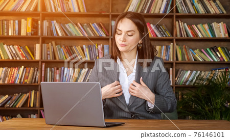Professional secretary types on laptop under fan wind 76146101